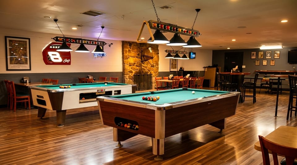 A spacious game room with two pool tables, a stone fireplace, and various seating areas.