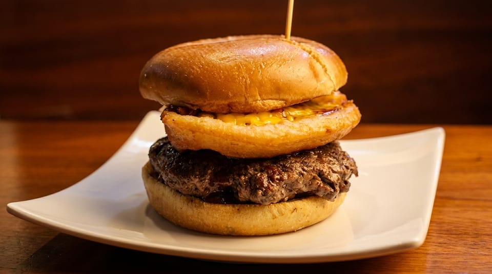 Juicy cheeseburger with a thick patty and melted cheese on a toasted bun, served on a white plate.