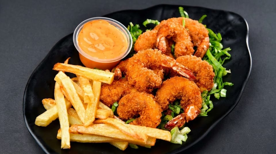Crispy fried shrimp and golden french fries served with a side of orange dipping sauce.